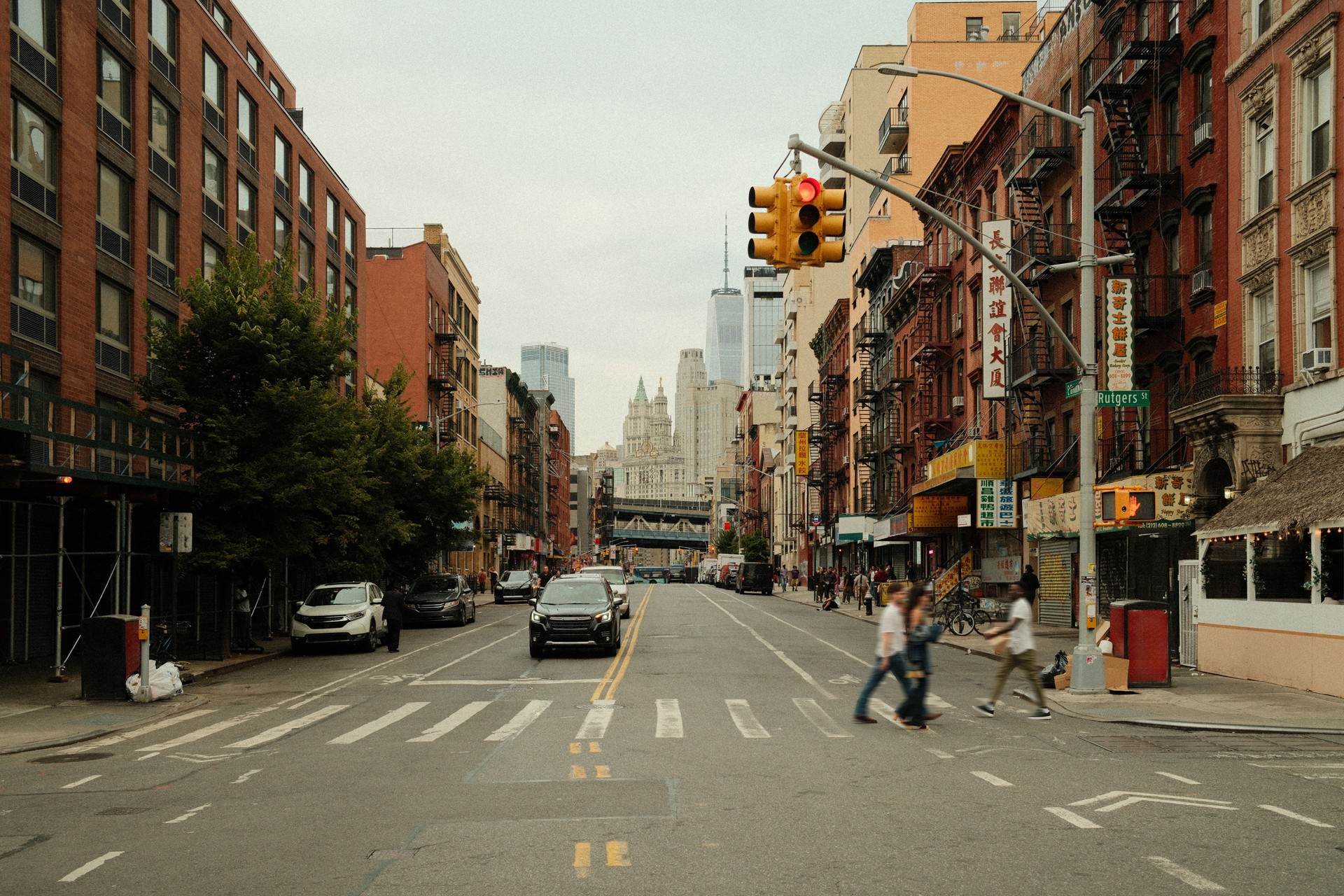People crossing street in chinatown new york city with one world trade center in background