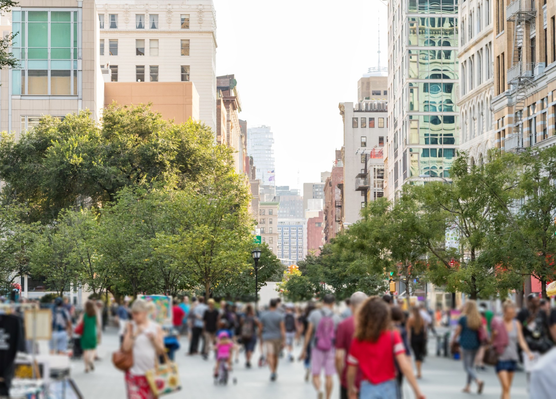 Crowds of people walking through Union Square Park in Manhattan New York City on a bright sunny day
